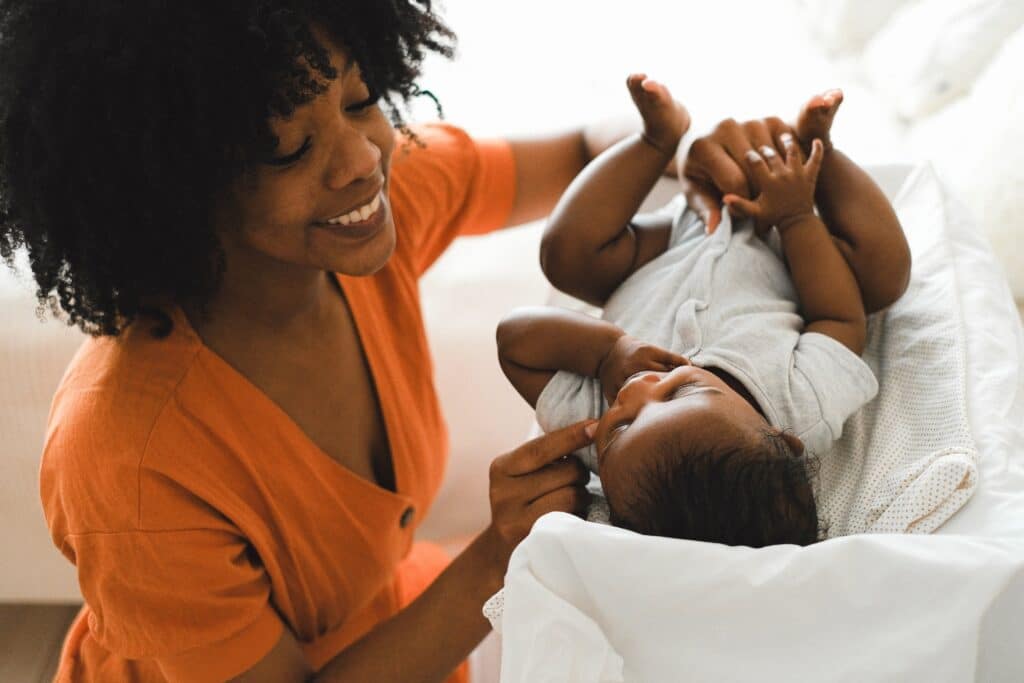 A mother in addiction recovery smiling and playing with her baby.