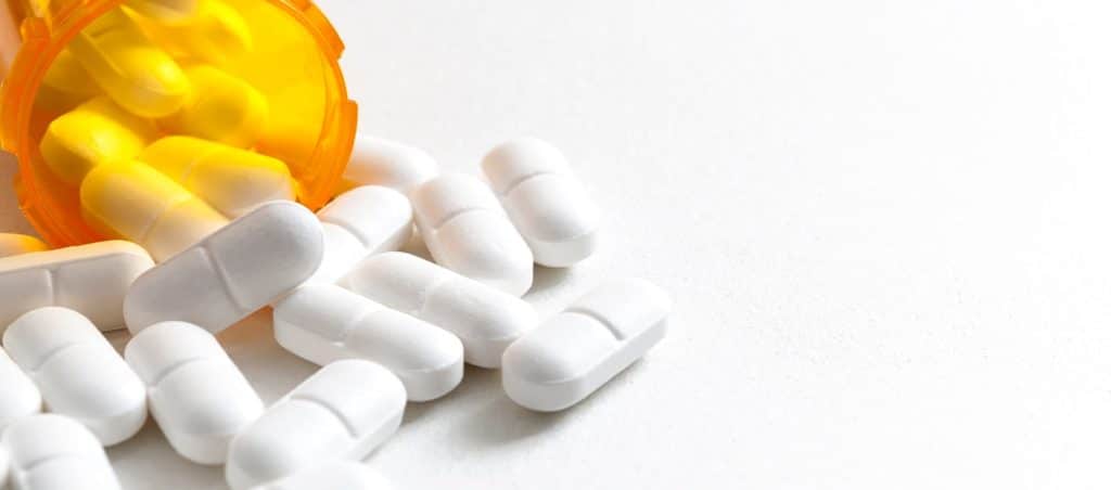 Opioids spilling out of an orange pill bottle