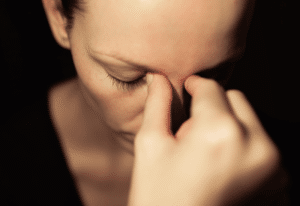Woman looking distraught pinching the top of her nose
