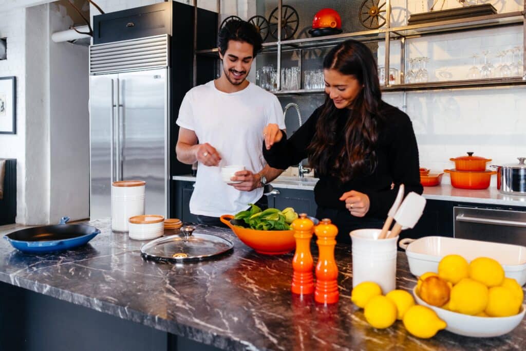 A couple in a kitchen, preparing a Thanksgiving salad together.