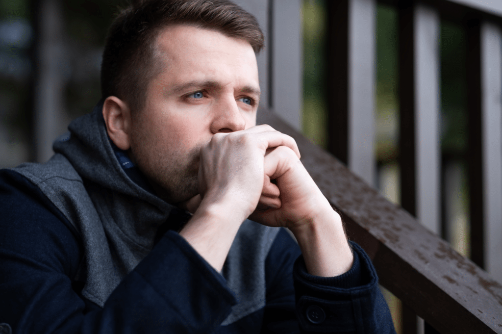 A man with his hands covering his mouth, possibly reflecting on personal challenges with substance use and contemplating joining an intensive outpatient program for treatment.