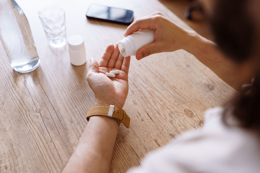A person pouring white pills into their hand, illustrating the dangers of mixing benzodiazepines and methadone.